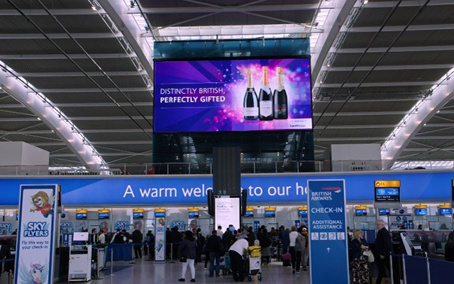 A large digital advertising screen in an airport check-in area